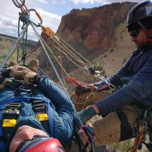 This image of patient packaging and litter attending presents Crux Rescue's provision of certified training courses for Rope Rescue Ops RRO certification with class instruction in anchor systems and more.